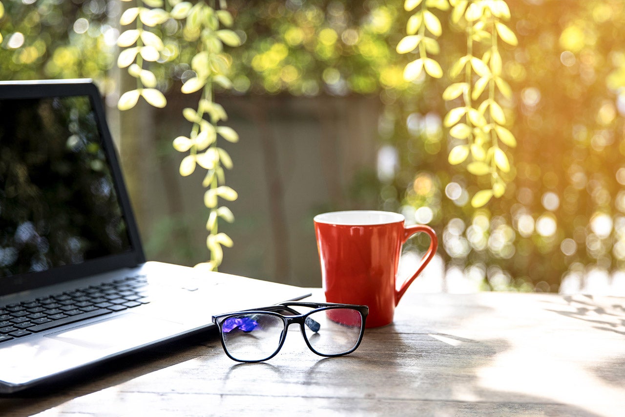 Laptop, Tasse und Brille auf einem Tisch