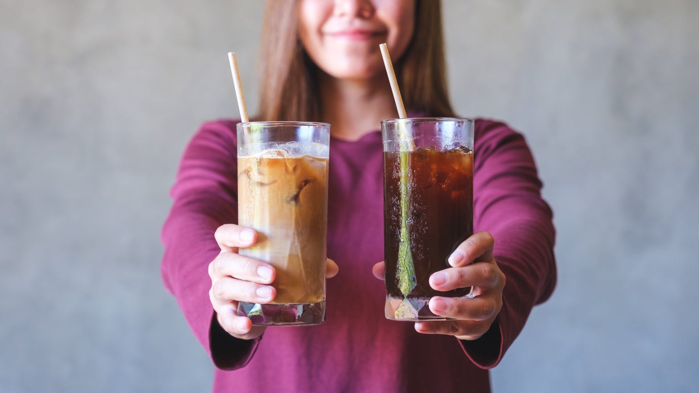 Frau mit zwei kalten Kaffees vor einer grauen Wand