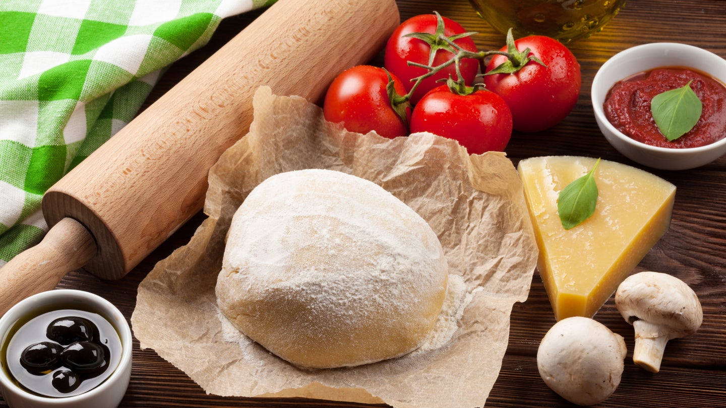 Teig mit einem Nudelholz und Zutaten