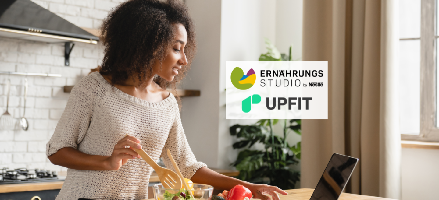 Junge Frau nutzt ihren Upfit-Ernährungsplan kostenlos auf einem Laptop beim Kochen